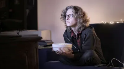 Pessoa assistindo filme no sofá em casa com streaming