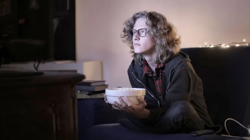 Pessoa assistindo filme no sofá em casa com streaming